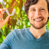 gentleman smiling and showing his invisalign mouthguard